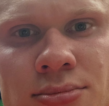 A close-up of a man's face with green eyes and freckled skin, his gaze meeting the camera directly—inviting the viewer to "look into his eyes" while some text reading "Flyknit Lunar..." is faintly visible in the background.