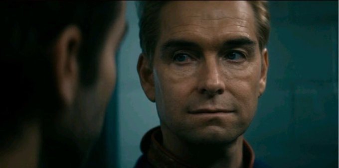 A close-up shot of a man with blue eyes looking intently at another person, who appears blurred in the foreground.