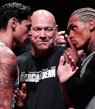 Ryan Garcia (left) and Conor Benn (right) face off intensely while promoter Eddie Hearn stands between them, with Garcia's shirt reading "Garcia vs Benn" ahead of their weekend bout where Garcia is favored at 70% on Polymarket.