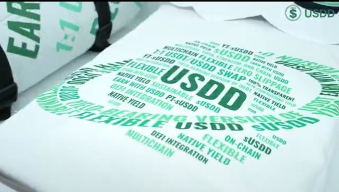 The image shows a white tote bag or promotional item featuring a circular word cloud design in green text, prominently displaying "USDD" at the center surrounded by related terms like "FLEXIBLE," "ZERO SLIPPAGE," "SUSTAINABLE," "DEFI INTEGRATION," "MULTICHAIN," "NATIVE YIELD," "ON-CHAIN," and "TRANSPARENT." This visual reinforces the post's message about USDD's evolution beyond basic stablecoin issuance into a full-fledged decentralized financial ecosystem, with the keywords highlighting the key features showcased at the WebX Asia conference.