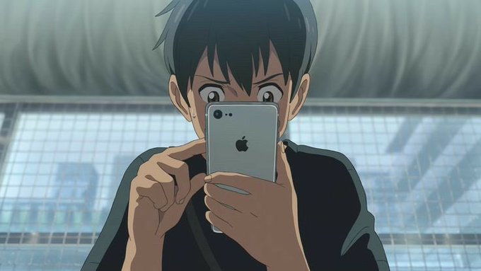 An anime-style illustration shows a young man with dark hair taking a selfie with a silver Apple iPhone, his wide eyes visible above the device.
