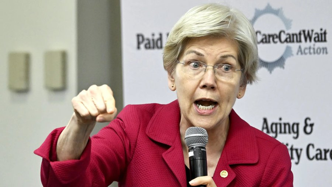 Senator Elizabeth Warren, wearing a red blazer, speaks passionately into a microphone with her fist raised, standing in front of a 'Paid Family Care Cant Wait Action' and 'Aging & [Disabili]ty Care' banner.