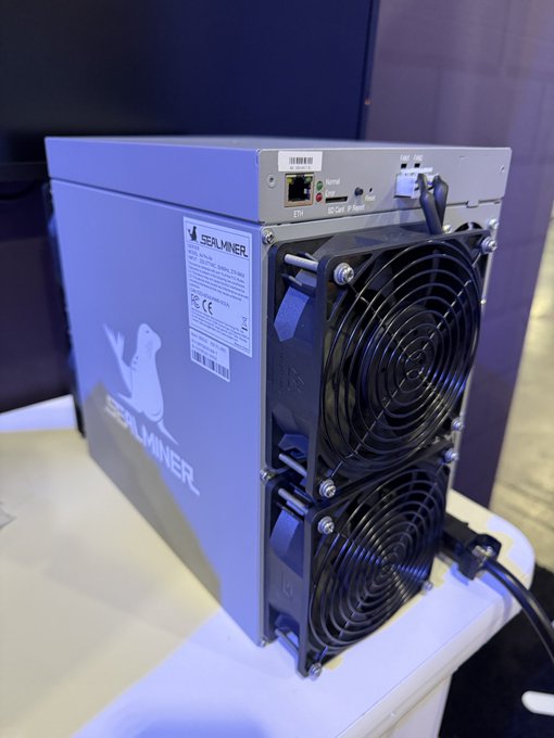 A SEALMINER cryptocurrency mining device, likely a Bitcoin miner, shown from the back with two cooling fans and Ethernet port visible.