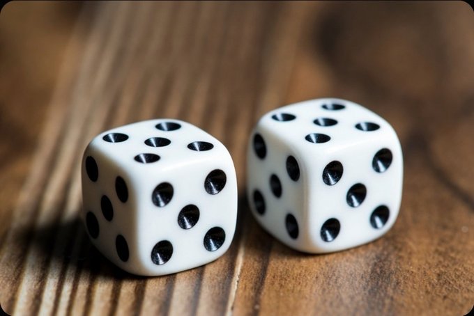 Two white six-sided dice with black pips rest on a wooden surface, their design emphasizing precision and balance—qualities essential to Coinkite's 0-Entropy Dice, a product aimed at providing cryptographically secure random number generation for cryptocurrency users.