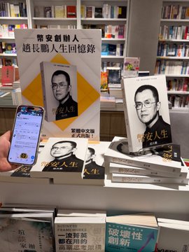 A copy of CZ's "Binance Life" is prominently displayed at the entrance of the Hong Kong Library, with several copies stacked on a table in front of bookshelves. The caption reads "幣安創辦人趙長鵬人生回憶錄" (Binance Founder Changpeng Zhao's Memoir), with the book featuring a black-and-white portrait of CZ on the cover, while a person holds up a phone in the foreground, likely to post about the find.