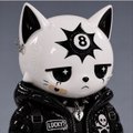 A small figurine or toy featuring a white cat-like character with a black star symbol on its forehead, wearing a black studded leather jacket.