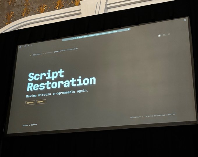 A photograph of a presentation screen displaying 'Script Restoration — Making Bitcoin programmable again' along with BIP numbers and references to 'great-script-restoration'.