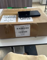 A Bitget Wallet package rests on a cardboard box, accompanied by a black wallet, celebrating the platform's 100 million users milestone as referenced in the congratulatory post.