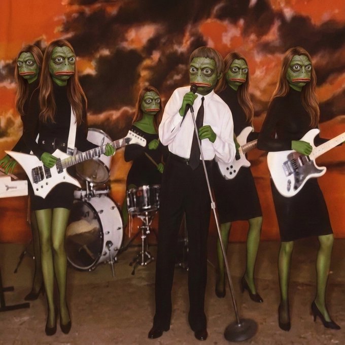 A surreal image shows a group of figures with green frog-like faces dressed as a band, with a man in a white shirt and tie singing into a microphone, surrounded by female bandmates playing guitars and drums against a fiery sky backdrop. The image plays on the phrase "Might as well face it..." by giving the performers literal frog faces, suggesting a humorous take on "facing the music."