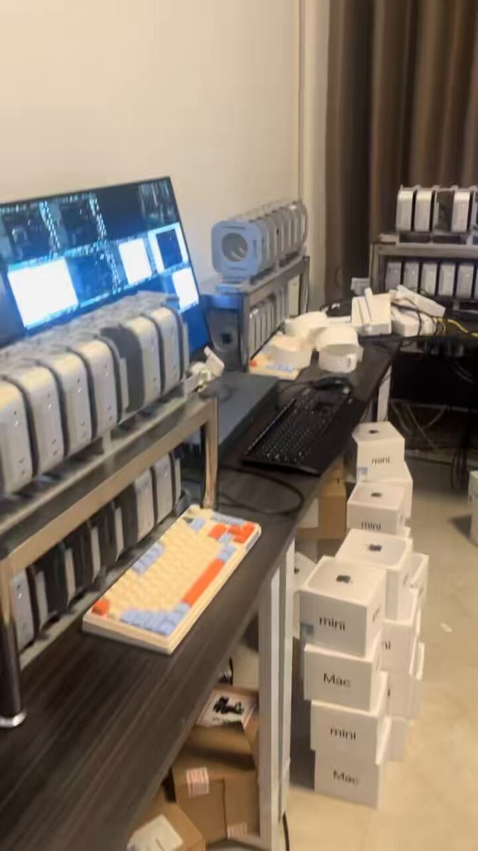 The image shows a computer desk with various electronic devices, including multiple computers, keyboards, mice, and other accessories such as boxes of mac minis. The desk also has a monitor that displays an image of a computer screen. The scene suggests that someone is using these devices for work or training purposes to earn tokens in exchange for computing power.