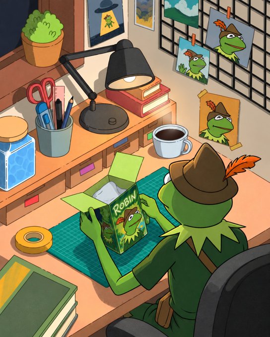 An illustration of a green frog-like character wearing a brown feathered hat, sitting at a desk and unboxing a figure labeled 'ROBIN'.