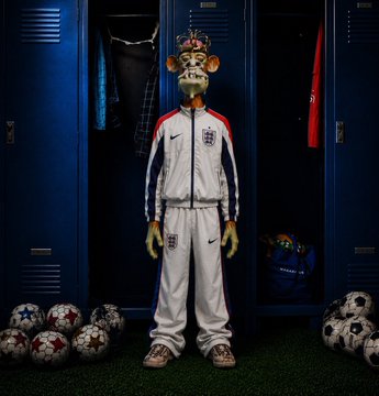 A giraffe wearing an England national football team tracksuit and a crown, standing in a locker room surrounded by soccer balls.