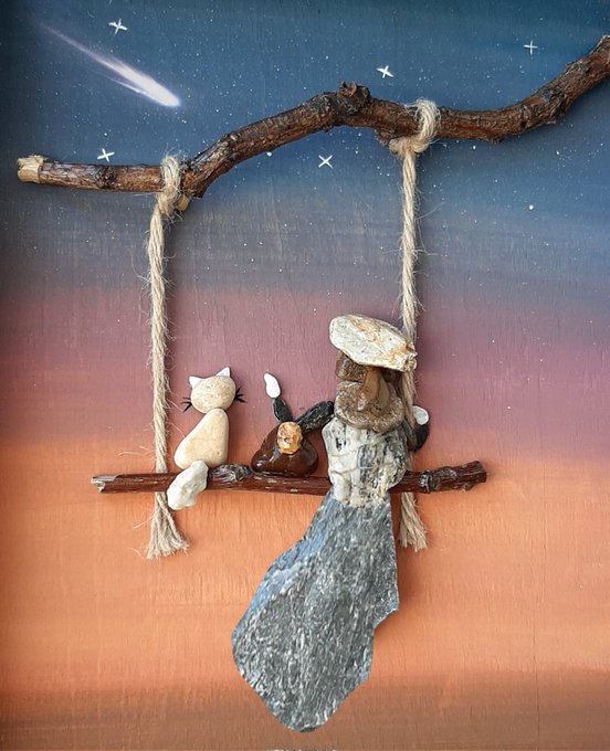 The image features a painting of a woman sitting on a swing, accompanied by two stuffed animals - a cat and a dog. The scene takes place at night under a starry sky with a branch hanging from the ceiling. The painting has been created using various materials such as wood, rope, and rocks to give it an artistic touch. The post where this image is displayed reads "QT quote your Tezos art #MadeCommunity1 #MadeArtBridge #MWellB".