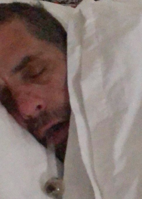 A bearded man sleeps peacefully in bed with his eyes closed, appearing completely exhausted after an intense night—humorously capturing the aftermath of a hypothetical 100x gain on the meme coin $LAPTOP.