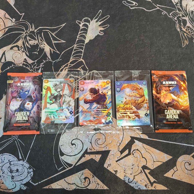Five Azuki "Garden Arena" trading card packs and a mix of holographic cards—including "Walters of the Waves," "Scarlett," and "Framboise Cat"—are laid out on a black playmat featuring anime-style artwork, previewing the fresh booster packs set to be opened.