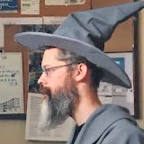 A profile photo of a bearded man wearing glasses and a gray wizard hat, resembling a Gandalf-style character.