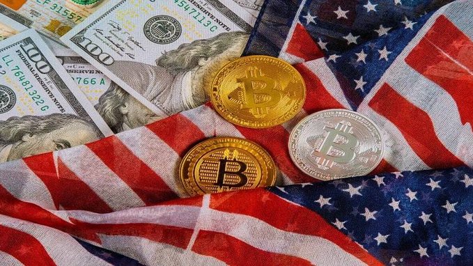 A close-up photo showing US dollar bills and physical Bitcoin tokens resting on an American flag.
