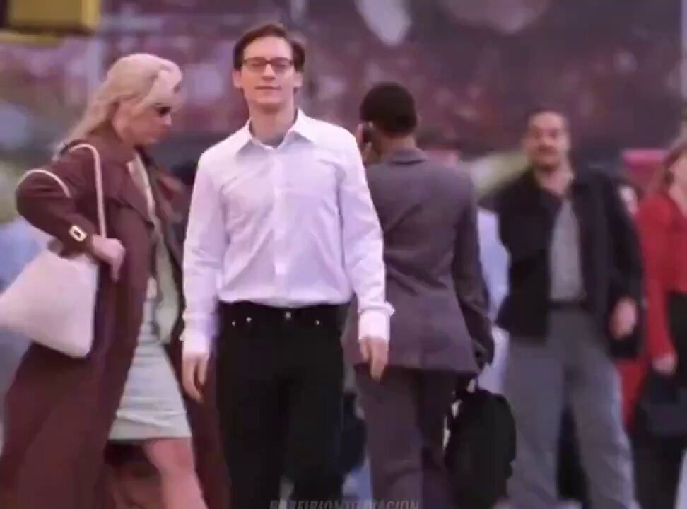 The image shows a group of people walking down a street, with one man wearing glasses and another carrying a backpack. The scene appears to be set in an urban environment where several individuals are engaged in various activities such as walking or standing. There is also a handbag visible on the ground near some of the pedestrians. 

The image seems to be related to the post about LI.FI, which discusses the concept of aggregating major bridge pools for better rates and stability. The people in the image could represent different individuals who are partaking in various activities or transactions that benefit from the stability and efficiency provided by LI.FI's platform.