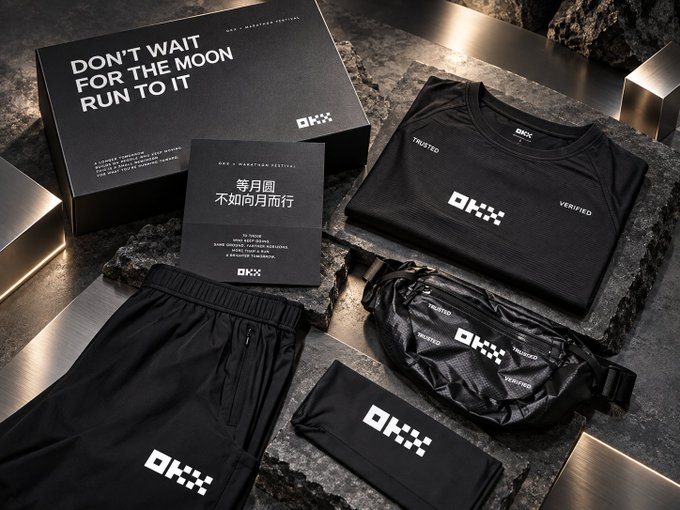OKX lifestyle festival merchandise display on dark stone, including a box reading 'DON'T WAIT FOR THE MOON RUN TO IT,' a card with '等月圆 不如向月而行,' and branded black apparel (shirt, shorts, fanny pack, and wristband) marked TRUSTED and VERIFIED.