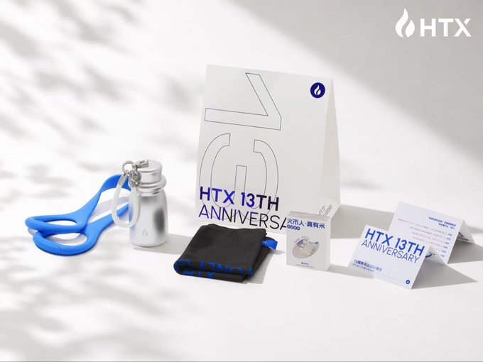 The image displays a collection of HTX 13th Anniversary merchandise, including a white gift bag prominently featuring "HTX 13TH ANNIVERSARY" text, a silver tumbler with a blue lanyard, a black drawstring pouch, and a card displaying "HTX 13TH ANNIVERSARY" details. This visual perfectly complements the accompanying post celebrating the unboxing of these commemorative items, with the tumbler particularly matching the user's excited mention of receiving a thermos as a gift.