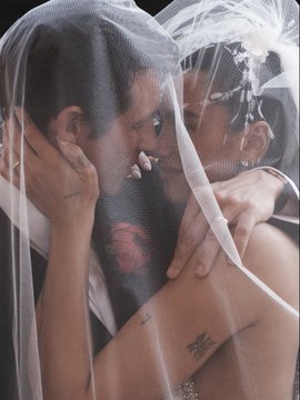 The image shows a man and woman embracing each other under a white veil. They are both dressed up for their wedding ceremony, with the man wearing a suit and tie while the woman has her hair styled in an elegant updo. The couple is standing close together, indicating a strong connection between them. In the background of the photo, there is text that reads "my GF said, 
'that could be us' but you keep believing in $ETH". This message seems to be related to the image and possibly serves as an inside joke or reference to their wedding day experience.