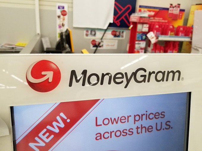 The image shows a display screen of a store, with the MoneyGram logo prominently displayed. The screen displays an advertisement for their new stablecoin, which allows users to send and receive payments across the U.S. and other countries. This new feature is part of MoneyGram's efforts to expand its payment options and reach customers in various locations.
