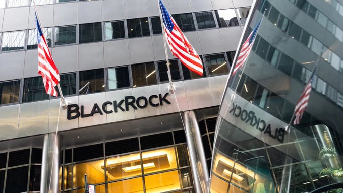 The image shows the exterior of a BlackRock office building with the company's name prominently displayed above the entrance, American flags flying outside, and the "BlackRock" signage reflected in a nearby window. The caption relates to the post by illustrating BlackRock's significant role in the Bitcoin ETF market, as its IBIT fund dominated Monday's $217 million inflow by capturing 95% of total deposits.