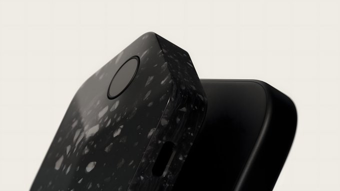 A close-up product shot of a black device featuring a speckled, textured surface and a circular button.