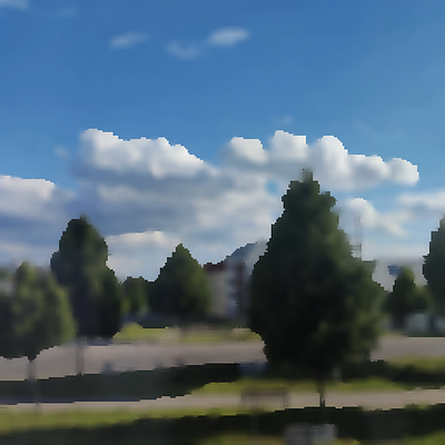 A blurry landscape photo showing green trees and a blue sky with white clouds, with indistinct buildings visible in the background.