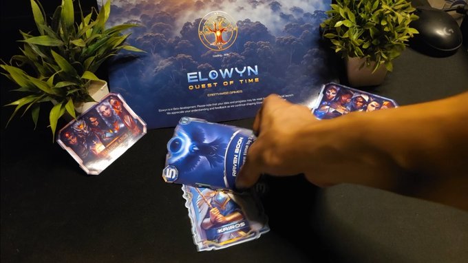 A hand reaches toward a deck of 'Elowyn: Quest of Time' card game booster packs and cards laid out on a table in front of the game box.
