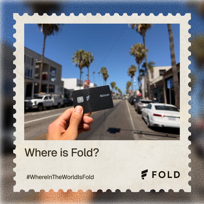 A promotional image styled as a stamp showing a hand holding a black 'bitcoin' branded card on a palm-tree-lined street, with text 'Where is Fold?' and hashtag '#WhereInTheWorldIsFold'.