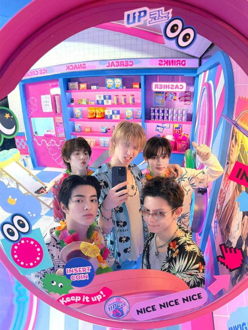 Five members of CORTIS pose for a mirror selfie in a colorful, pink-hued themed photo booth or set, dressed in tropical print shirts and colorful accessories. The image is decorated with playful stickers including "INSERT COIN," "Keep it up!," "NICE NICE NICE," and a "UP코노" banner at the top, promoting the group's "Mirror selfie" EP.15 of their UPCONO series releasing on 2026.07.30.