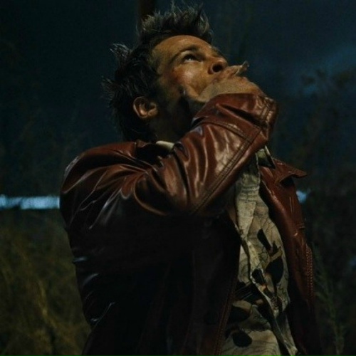 A cinematic shot of a man in a leather jacket looking upward with his hand near his mouth, set against a dark nighttime background.