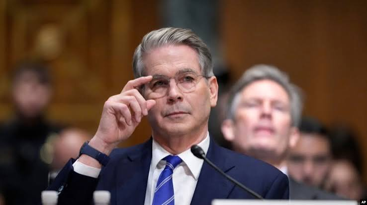 Scott Bessent, identified by AP credit, adjusts his glasses while seated at what appears to be a congressional hearing.