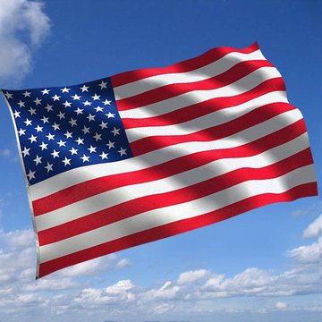 An American flag waves against a blue sky with scattered clouds.
