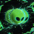 A highly distorted, low-resolution digital image showing a green alien head with large black eyes surrounded by a chaotic, glowing green background.