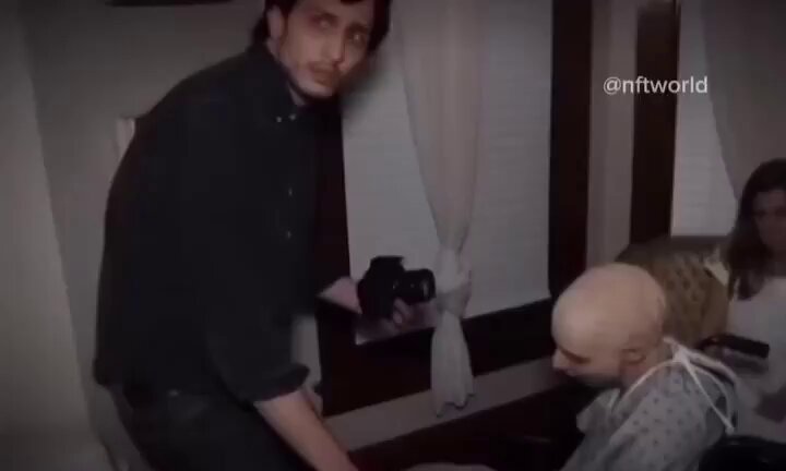 In the image, a man dressed in black is standing next to another person who has had his head shaved due to cancer treatment. They are positioned in front of an open window with white curtains. The man appears to be holding a camera or a book near his face as if he's capturing something or reading it out loud for someone else.

The caption provided in the image states "He bought $BTC at $126,000, $ETH at $4,000 and $SOL at $. Focus on what is in the image and how it relates to this post." This could be a message from someone named "nftworld" who wrote the caption. It seems that they might be talking about an event or a sale happening outside of the window where the man is standing, possibly related to the person's baldness as a result of cancer treatment.