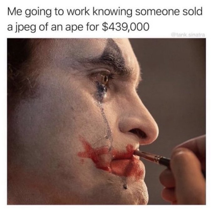 A meme captioned 'Me going to work knowing someone sold a jpeg of an ape for $439,000' by @tank.sinatra, showing a close-up of a man's face being painted with clown makeup, featuring a painted tear.