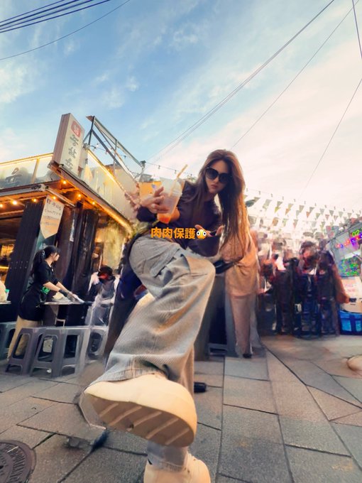 A young woman wearing sunglasses posing at what appears to be a Taiwanese night market, with Chinese text overlay reading '肉肉保護🐶🫶' (Protecting the meat/meatball) as she holds a food item.