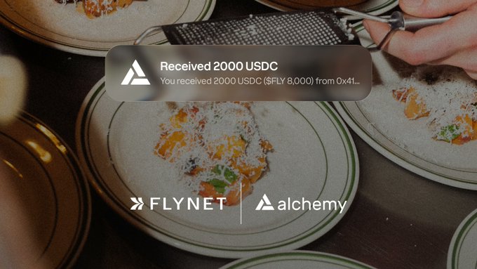 An overhead shot of plates of pasta being served, overlaid with a notification reading "Received 2000 USDC. You received 2000 USDC ($FLY 8,000) from 0x41..." and logos for Flynet and Alchemy, illustrating the post's claim that Alchemy has simplified the deposit confirmation process for builders.
