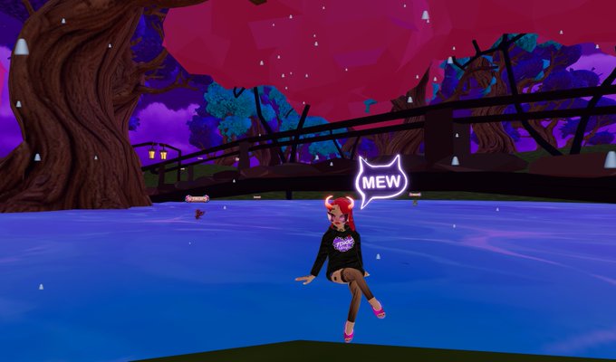 A screenshot from a virtual 3D world shows an anime-styled avatar with pink hair and cat ears sitting on the edge of a blue body of water, with a speech bubble displaying the text "MEW" against a backdrop of a pink-leafed tree, purple sky, and a wooden bridge.