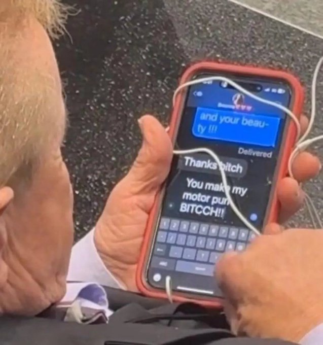 An older man holds a smartphone with a red case, showing a text conversation with messages that read 'Thanks bitch' and 'You make my motor purr BITCCH!!!'.