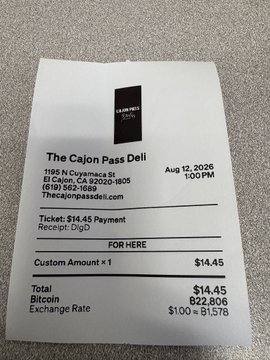A receipt from The Cajun Pass Deli dated Aug 12, 2025 at 1:00 PM, showing a payment of $14.45 with a Bitcoin exchange rate of $100 = ₿1.578 and total Bitcoin amount of ₿2.806.