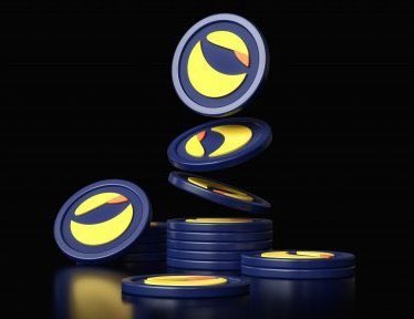 A 3D rendering of dark blue and yellow coins featuring a stylized face logo, stacked and scattered against a black background.