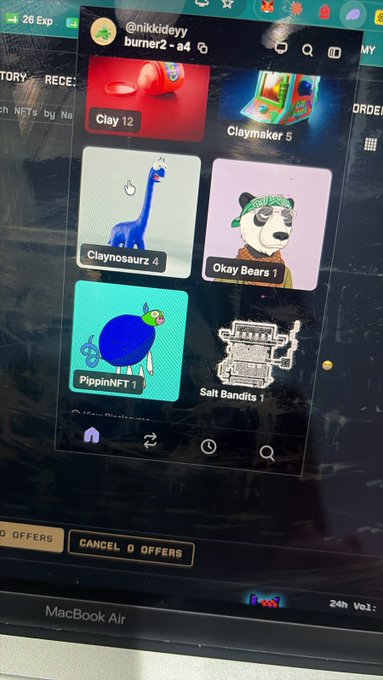 A MacBook Air screen displays a burner wallet (visible as @nikkideyy burner2-a4) containing NFTs including Clay 12, Claymaker 5, Claynosaurz 4, Okay Bears 1, PippinNFT 1, and Salt Bandits 1. The image illustrates the post's punchline, showing that the user's "sold" Claynosaurz NFT has actually been sitting unused in a burner wallet this whole time.
