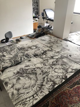 A bedroom features a large bed with an intricate black-and-white anime-style bedsheet, alongside a computer desk setup with a monitor and chair.