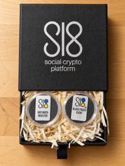 A black gift box from "social crypto platform" (SCP) containing two tins of mustard, opened to reveal wood shavings packaging.