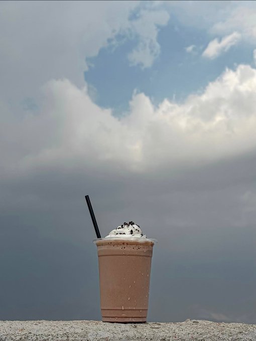 The image features a cup of coffee with whipped cream sitting outside, possibly at an outdoor cafe or during a break from work. The sky behind the cup has clouds, suggesting that it might be a cloudy day. The photo also includes text that reads "GM gQuip The biggest challenge in information markets isn't creating content; it's finding what provides real value." This could be related to the coffee and its presentation or even the weather conditions.