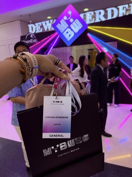 A photo at a 'Night Bus' event showing a hand holding a black gift bag and a VIP lanyard labeled 'CYNTHIA RODRIGUES LIMITED GENERAL' in a club-like setting.