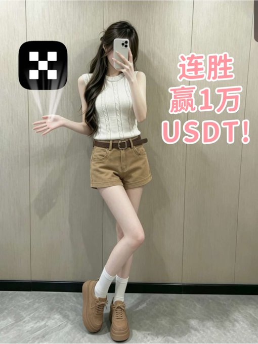 A woman takes a mirror selfie wearing a sleeveless cream sweater, brown belted shorts, and tan platform shoes; the image features an OKX logo and Chinese text reading '连胜 赢1万 USDT!' (Winning streak, win 10,000 USDT!).